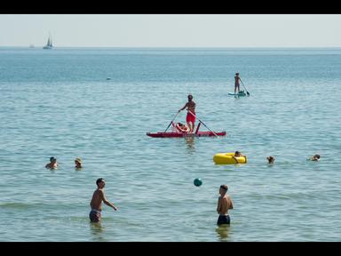 Spiaggia affollata con ombrelloni e bagnanti durante il picco delle vacanze estive