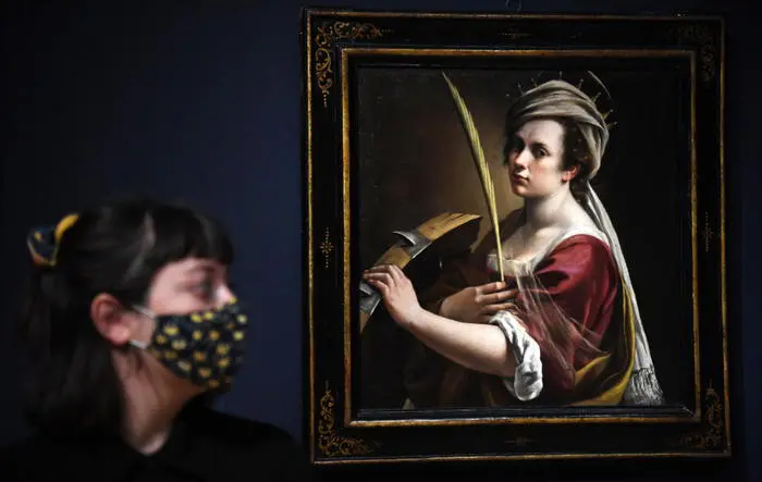 epa08705876 A model poses in front of a painting by Italian Baroque artist Artemisia Gentileschi, titled 'Self Portrait as Saint Catherine of Alexandria', during a preview of the exhibition 'Artemisia' at the National Gallery in London, Britain 29 September 2020. The exhibit will open to the public on 03 October 2020 and run until 24 January 2021. EPA/FACUNDO ARRIZABALAGA