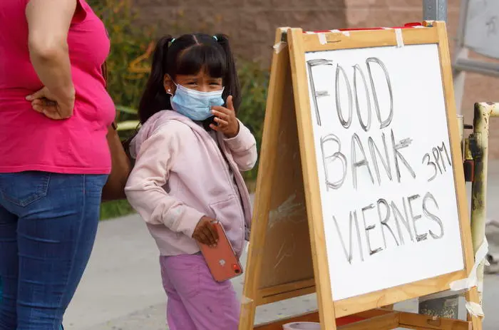 epa08370086 Local residents queue to receive free food bags at a weekly food bank giveaway as a result of the coronavirus health crisis in Santa Ana, California, USA, 17 April 2020. According to reports, an estimated 1,000 people lined up for nearly three hours to receive food, as unemployment increase due to coronavirus restrictions. EPA/EUGENE GARCIA