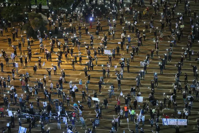 epa08372029 Israelis turn on their mobile phone lights as they protest against government corruption and for democracy at Rabin square in Tel Aviv, Israel, 15 April 2020. Reports state that around 2,000 people took part in the demonstration keeping two meters distance from each other in order to prevent the spread of the SARS-CoV-2 coronavirus which causes he Covid-19 disease. EPA/ABIR SULTAN
