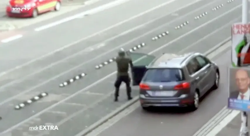 Un frame di uno degli attentatori di Halle, 9 ottobre 2019. Un uomo vestito con una divisa verde scuro e un elmetto che spara colpi da una grossa pistola che rilascia notevoli sbuffi di fumo bianco. ANSA/WWW.MDR.DE ++ NO SALES, EDITORIAL USE ONLY ++
