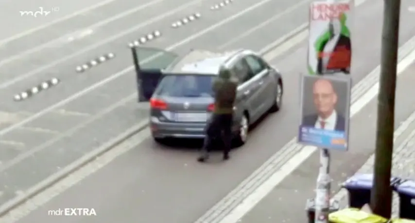 Un frame di uno degli attentatori di Halle, 9 ottobre 2019. Un uomo vestito con una divisa verde scuro e un elmetto che spara colpi da una grossa pistola che rilascia notevoli sbuffi di fumo bianco. ANSA/WWW.MDR.DE ++ NO SALES, EDITORIAL USE ONLY ++