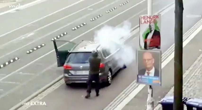 Un frame di uno degli attentatori di Halle, 9 ottobre 2019. Un uomo vestito con una divisa verde scuro e un elmetto che spara colpi da una grossa pistola che rilascia notevoli sbuffi di fumo bianco. ANSA/WWW.MDR.DE ++ NO SALES, EDITORIAL USE ONLY ++