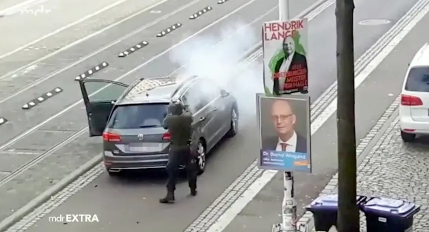 Un frame di uno degli attentatori di Halle, 9 ottobre 2019. Un uomo vestito con una divisa verde scuro e un elmetto che spara colpi da una grossa pistola che rilascia notevoli sbuffi di fumo bianco. ANSA/WWW.MDR.DE ++ NO SALES, EDITORIAL USE ONLY ++