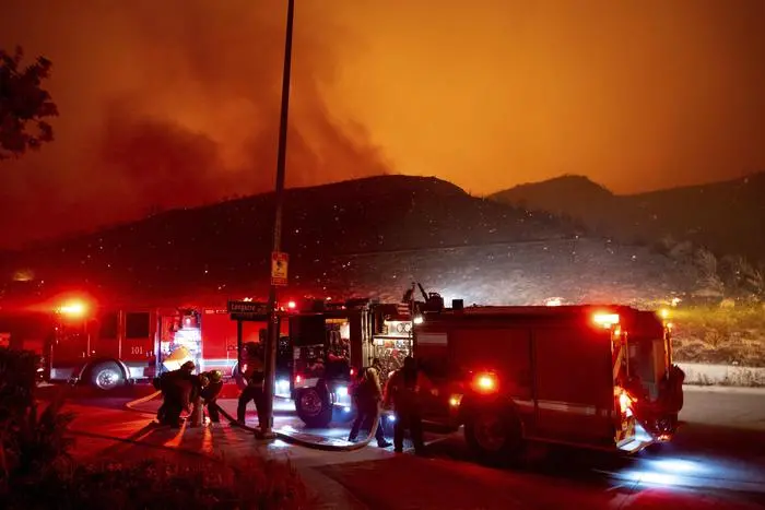Firefighters refill their truck with water along Sesnon Boulevard early Friday morning, Oct. 11, 2019, as flames burn on the hills in Granada Hills, Calif. (David Crane/The Orange County Register via AP) [CopyrightNotice: Los Angeles Daily News/SCNG]