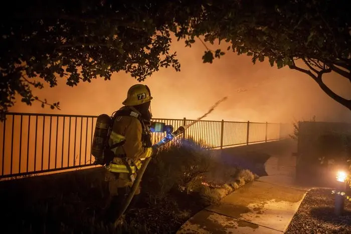 epa07912587 A firefighter using a breathing apparatus works to protect homes during the Saddleridge Fire in Sylmar, California, USA, 11 October 2019. The fire had burned over 3,000 acres as of 11 October 2019. According to the latest reports the fire is progressing quickly due to the strong winds, prompting an evacuation of the nearby inhabitants. EPA/CHRISTIAN MONTERROSA