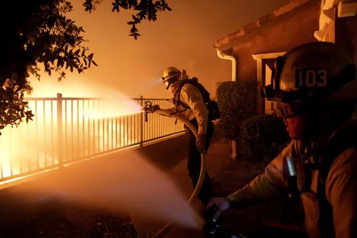 In this Thursday, Oct. 10, 2019 photo, Los Angeles City firefighters battle the Saddleridge fire near homes in Sylmar, Calif. (ANSA/AP Photo/Michael Owen Baker) [CopyrightNotice: Copyright 2019 The Associated Press. All rights reserved.]