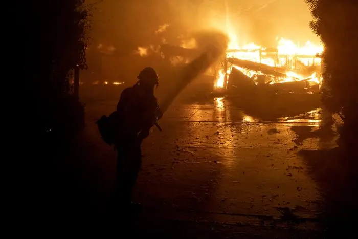 A firefighter sprays water on a fully engulfed house on Jolette Way in Granada Hills North, Calif., early Friday morning, Oct. 11, 2019. David Crane/The Orange County Register via AP) [CopyrightNotice: Los Angeles Daily News/SCNG]