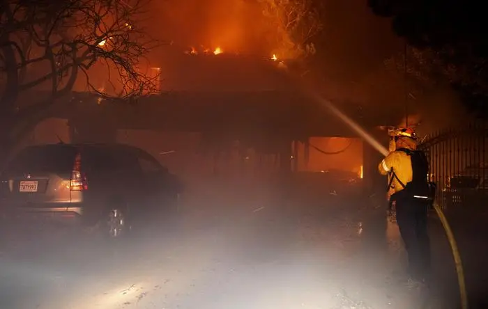A firefighter sprays water on a fully engulfed house on Jolette Way in Granada Hills North early Friday morning, Oct. 11, 2019. (David Crane/The Orange County Register via AP) [CopyrightNotice: Los Angeles Daily News/SCNG]