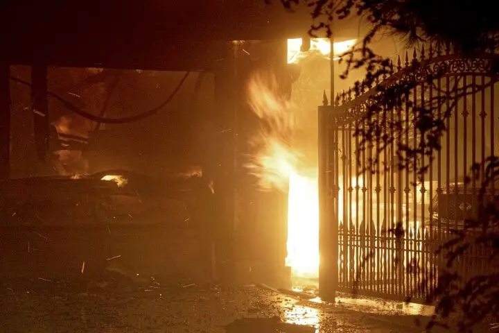 Flames shoot out from the front of a house on Jolette Way in Granada Hills North, Calif., early Friday morning, Oct. 11, 2019. (David Crane/The Orange County Register via AP) [CopyrightNotice: Los Angeles Daily News/SCNG]