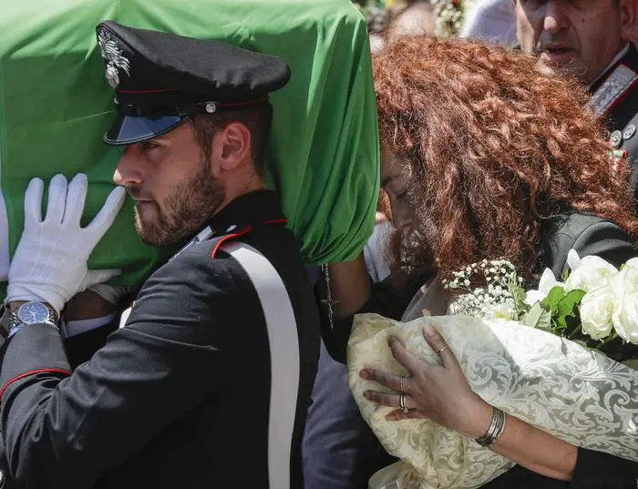 Carabinieri officer Mario Cerciello Rega's wife, Rosa Maria, right, follows the coffin containing the body of her husband during his funeral in his hometown of Somma Vesuviana, near Naples, southern Italy, Monday, July 29, 2019. Two American teenagers were jailed in Rome on Saturday as authorities investigate their alleged roles in the fatal stabbing of the Italian police officer on a street near their hotel. (ANSA/AP Photo/Andrew Medichini) [CopyrightNotice: Copyright 2019 The Associated Press. All rights reserved.]