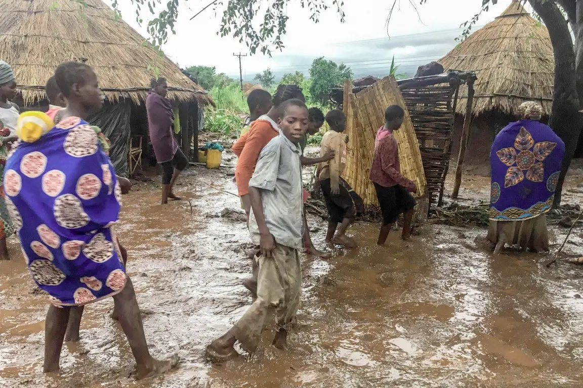 epa07446406 Inhabitants of Chiluvi, a village in central Mozambique, walk along a flooded and muddy street after Cyclone Idai and Floods that hit the region, in Nhamatanda, Mozambique, 13 March 2019 (Issued 18 March 2019). Chiluvo, together with Nhamatanda, Sofala, illustrates the tragedy that is experienced throughout the central region of Mozambique, especially in the provinces of Sofala and Manica, where there will already be between 73 and 84 confirmed deaths, according to official figures, leaving thousands in need of relief for remaining isolated in a flooded region. EPA/ANDRE CATUEIRA BEST QUALITY AVAILABLE