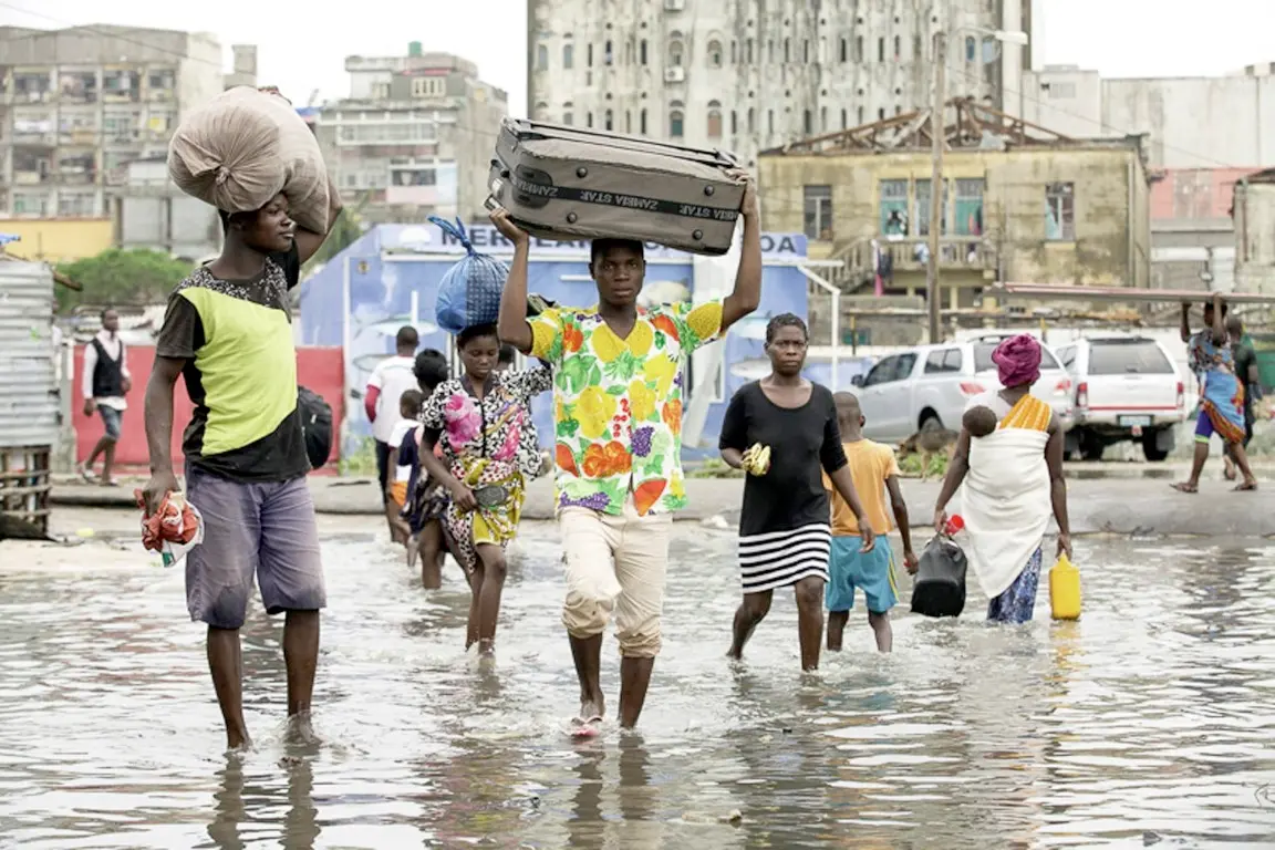 In this photo taken on Friday, March 15, 2019 and provided by the International Red Cross, people carry their personal effects after Tropical Cyclone Idai, in Beira, Mozambique. Mozambique's President Filipe Nyusi says that more than 1,000 may have by killed by Cyclone Idai, which many say is the worst in more than 20 years. Speaking to state Radio Mozambique, Nyusi said Monday, March 18 that although the official death count is currently 84, he believes the toll will be more than 1,000. (Denis Onyodi/IFRC via AP) [CopyrightNotice: IFRC Climate Centre]
