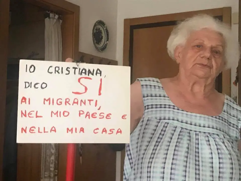 annamaria cartello pro migranti arco collegiata con don walter sommavilla