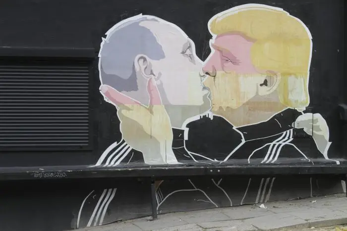 epa05455316 A view of a graffiti mural by Lithuanian artist Mindaugas Bonanu depicting US Republican presidential candidate Donald Trump (R) kissing Russian President Vladimir Putin on the wall of a barbacue restaurant Keule Ruke in Vilnius, Lithuania, 04 August 2016. EPA/VALDA KALNINA