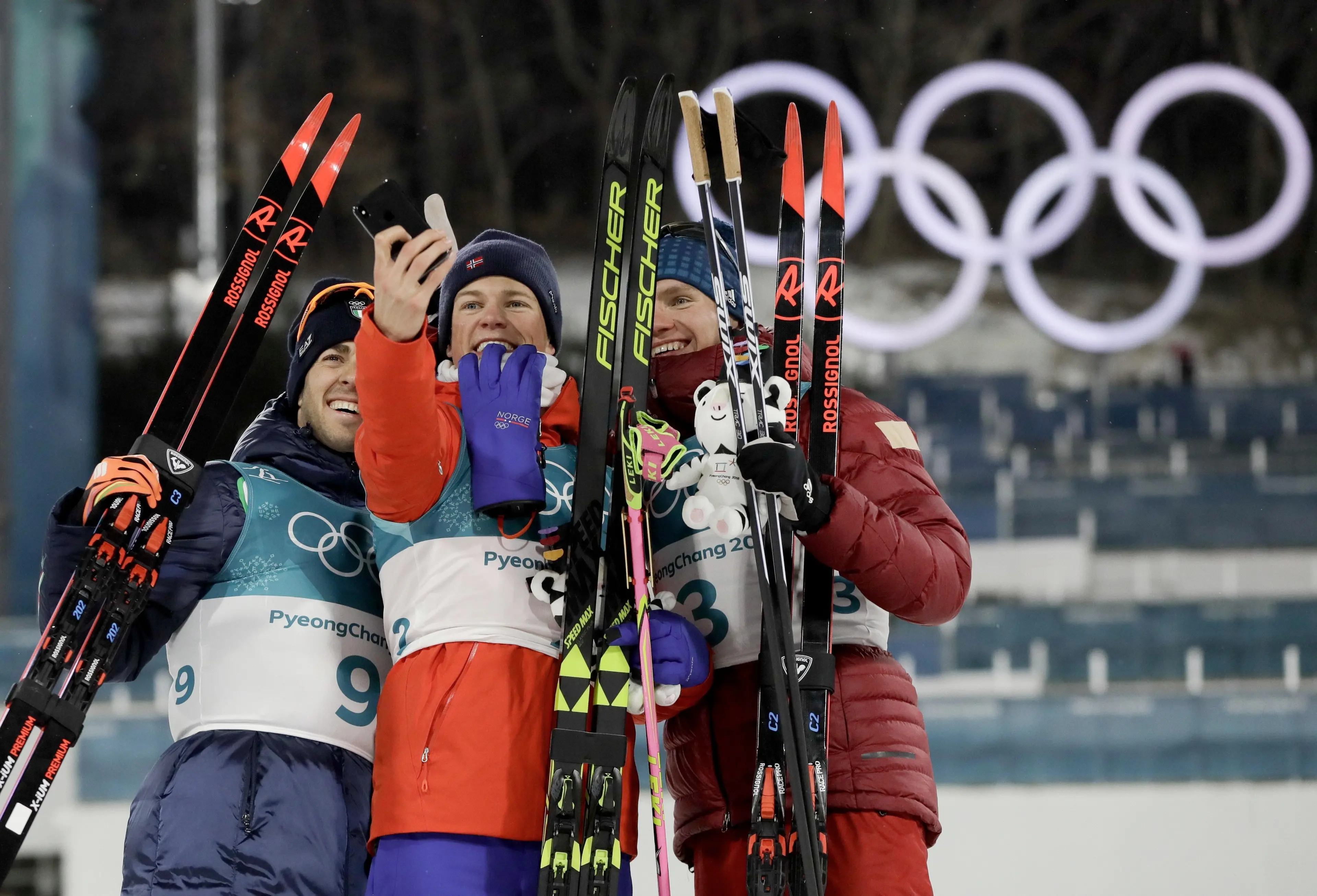 Gold medal winner Johannes Hoesflot Klaebo, of Norway, is flanked by silver medal winner Federico Pellegrino, of Italy, left, and bronze medal winner Alexander Bolshunov, of the team from Russia, after the men's cross-country skiing sprint classic at the 2018 Winter Olympics in Pyeongchang, South Korea, Tuesday, Feb. 13, 2018. (ANSA/AP Photo/Kirsty Wigglesworth) [CopyrightNotice: Copyright 2018 The Associated Press. All rights reserved]