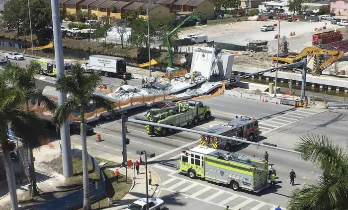 Emergency personnel responds to a collapsed pedestrian bridge connecting Florida International University Florida International on Thursday, March 15, 2018 in the Miami area. The brand-new pedestrian bridge collapsed onto a highway crushing at least five vehicles. Several people were seen being loaded into ambulances and authorities said they were searching for people. (Roberto Koltun/The Miami Herald via AP) [CopyrightNotice: Copyright 2018 The Associated Press. All rights reserved.]