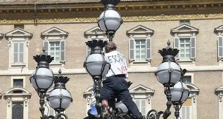Sale su lampione per protesta mentre passa il Papa a San Pietro