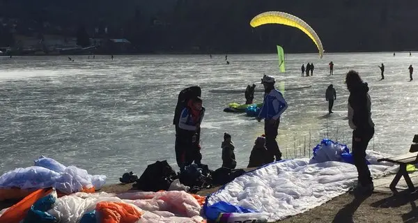 Subacquei sotto il ghiaccio e parapendisti sopra il lago