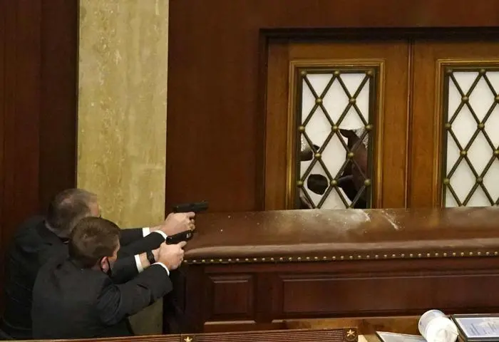 WASHINGTON, DC - JANUARY 06: U.S. Capitol police officers point their guns at a door that was vandalized in the House Chamber during a joint session of Congress on January 06, 2021 in Washington, DC. Congress held a joint session today to ratify President-elect Joe Biden's 306-232 Electoral College win over President Donald Trump. A group of Republican senators said they would reject the Electoral College votes of several states unless Congress appointed a commission to audit the election results. Drew Angerer/Getty Images/AFP == FOR NEWSPAPERS, INTERNET, TELCOS & TELEVISION USE ONLY ==