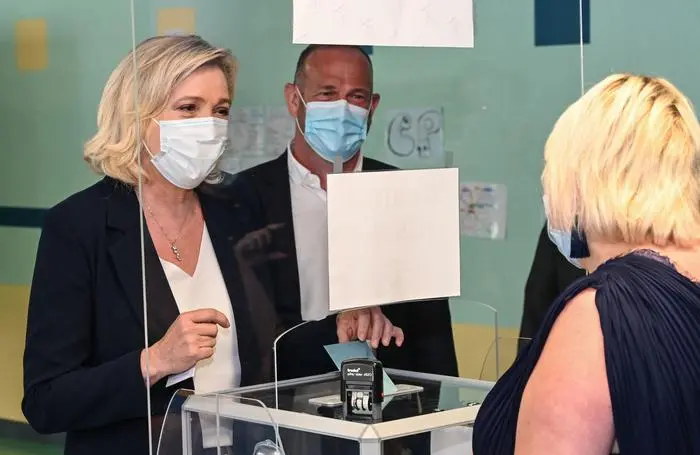 French far-right Rassemblement National (RN) party's leader and member of parliament Marine Le Pen casts her vote, next to RN mayor of Henin-Beaumont Steeve Briois (R) at a polling station in Henin-Beaumont, northern France, for the first round of the French regional elections on June 20, 2021. (Photo by DENIS CHARLET / AFP)