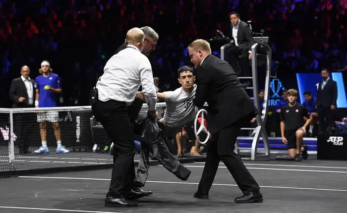 epa10201720 A climate change activist protesting against UK private jets is carried from the court after lighting his right arm on fire during the Laver Cup tennis tournament at the O2 Arena in London, Britain, 23 September 2022. EPA/ANDY RAIN