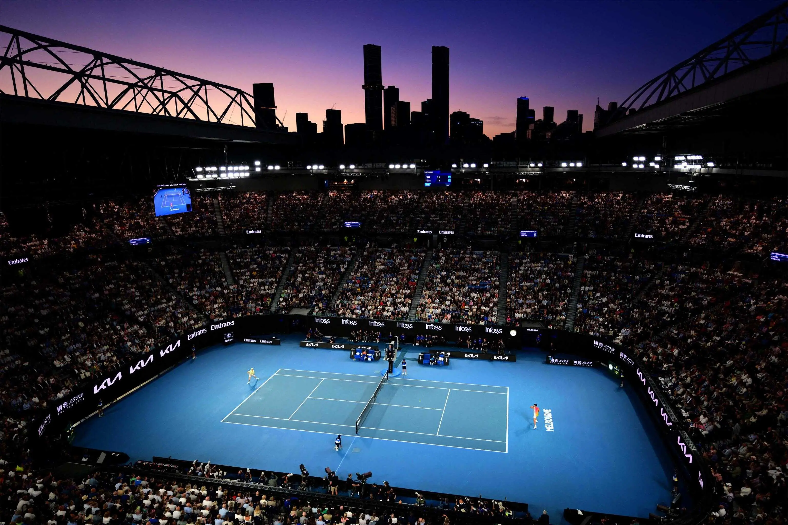 The sun sets as Italy's Jannik Sinner (L) hits a return against USA's Ben Shelton during their men's singles semi-final match on day thirteen of the Australian Open tennis tournament in Melbourne on January 24, 2025. (Photo by Yuichi YAMAZAKI / AFP) / -- IMAGE RESTRICTED TO EDITORIAL USE - STRICTLY NO COMMERCIAL USE --