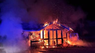 Fiamme avvolgono un deposito in legno durante la notte con vigili del fuoco in intervento d'emergenza