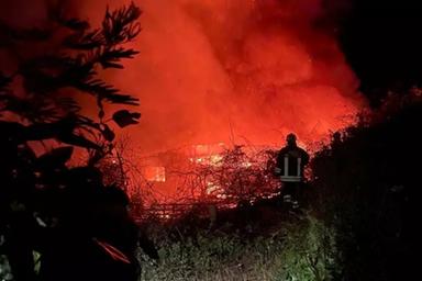Strada rurale calabrese con erba alta e fumo, incendio boschivo sullo sfondo