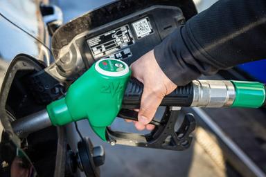 Pompa di benzina con prezzi esposti, automobilista rifornisce auto in stazione di servizio