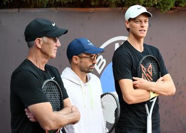 Allenatore durante una conversazione su un campo da tennis, con focus sulla gestione emotiva di un campione